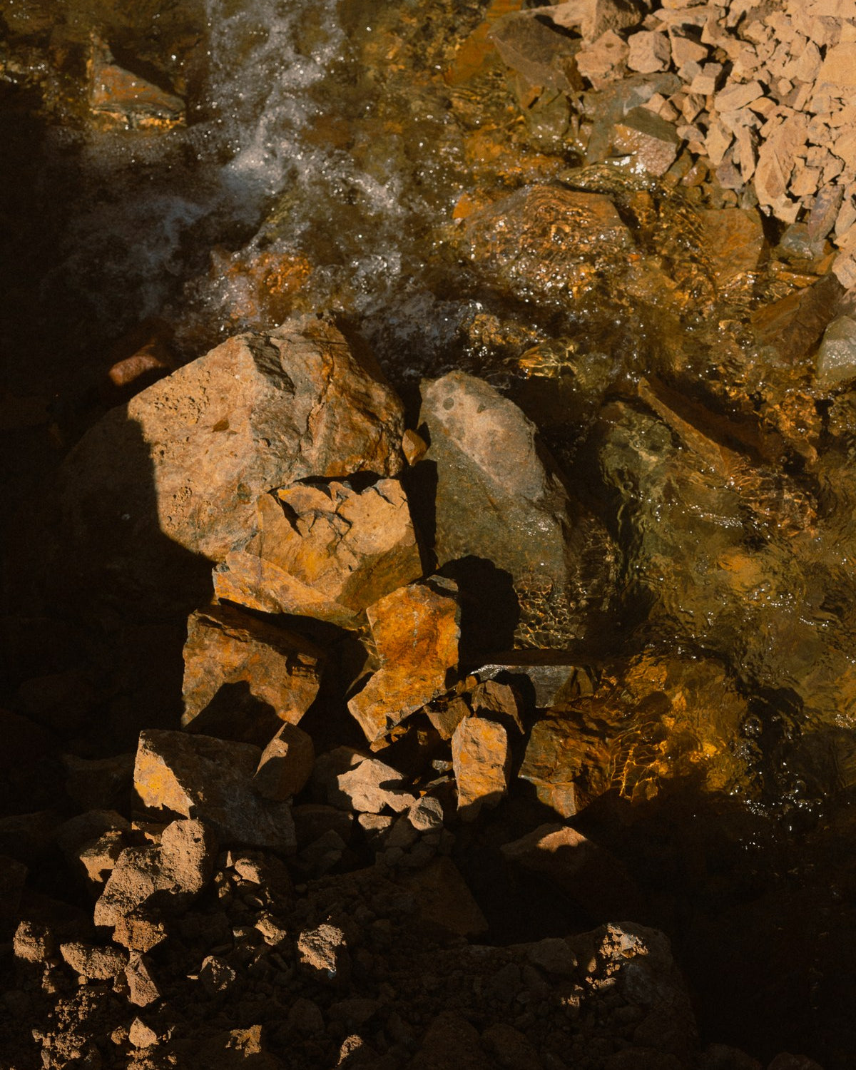 Sunlit ochre rocks in shallow running water