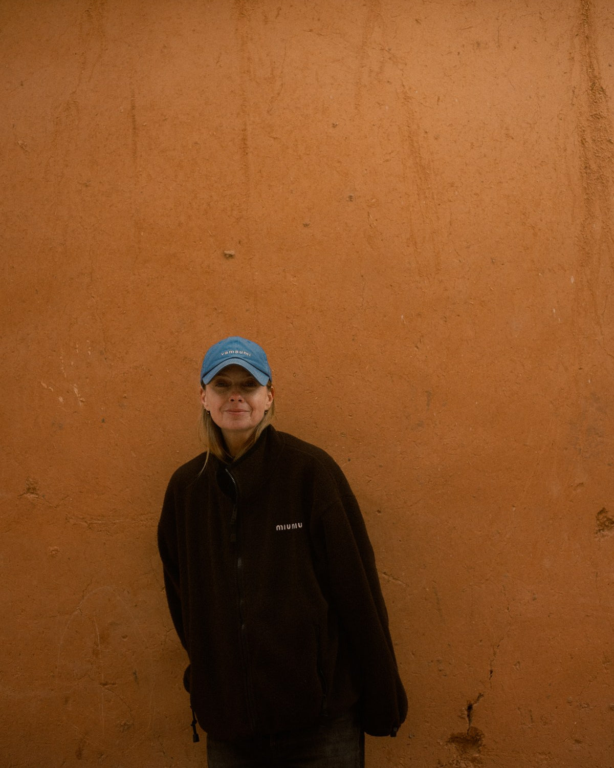 Lyn Harris against a plain ochre clay wall