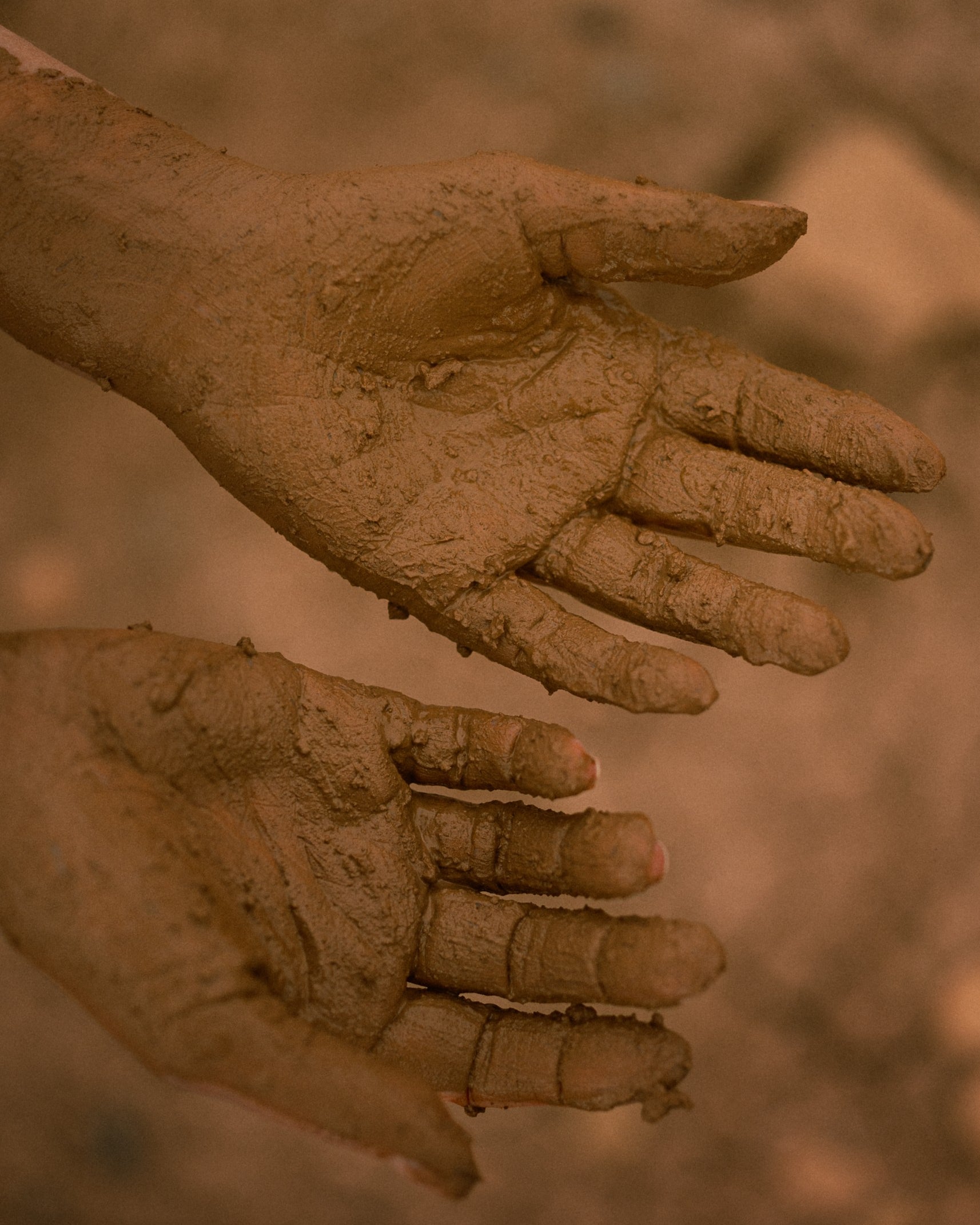 Two hands coated in wet clay