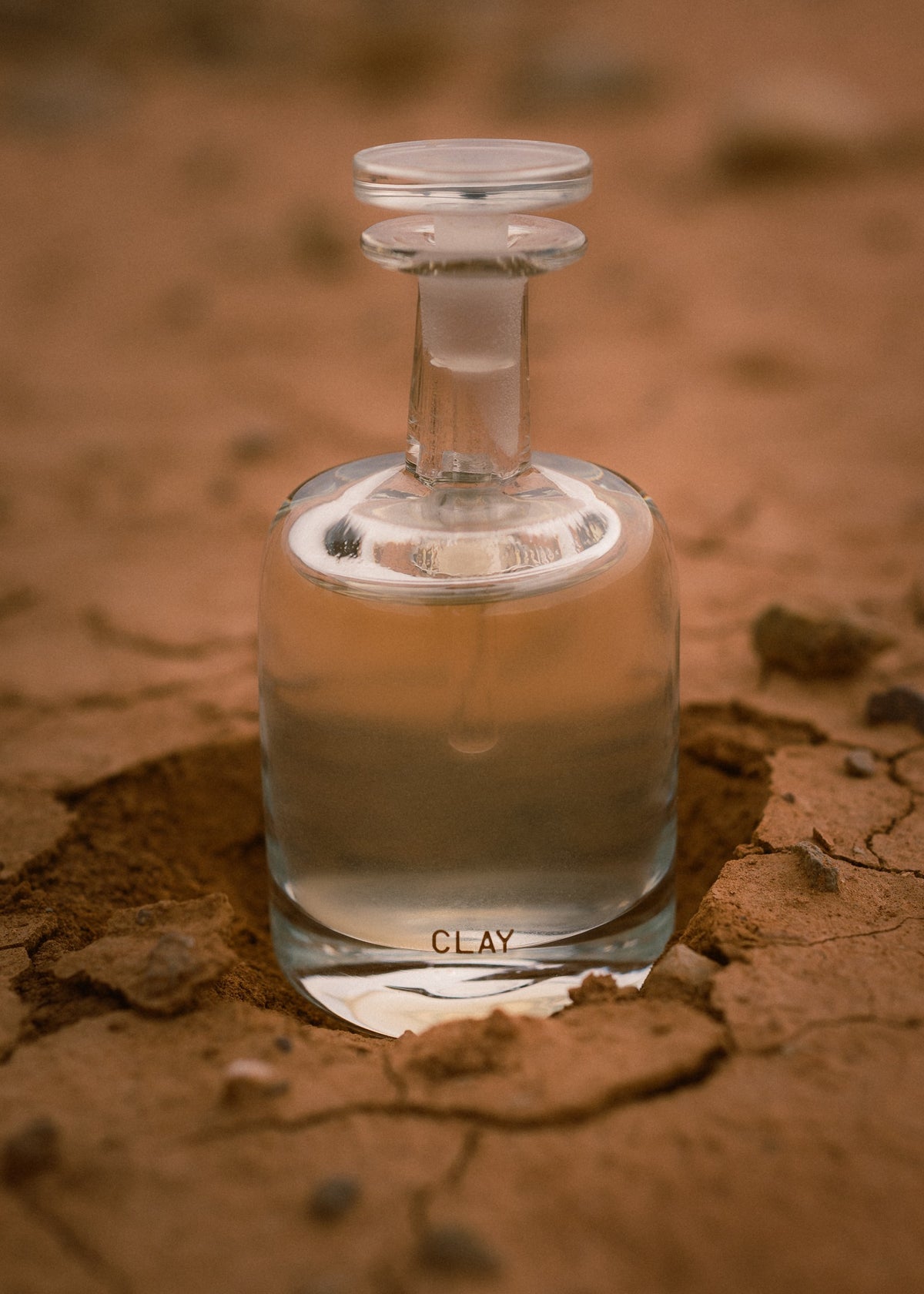 CLAY hand blown eau de parfum on cracked red earth