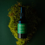 Rain Wood Deodorant bottle laid on a clump of moss, label facing the camera