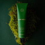 Rain Wood Hand Cream tube resting on a clump of bright green moss